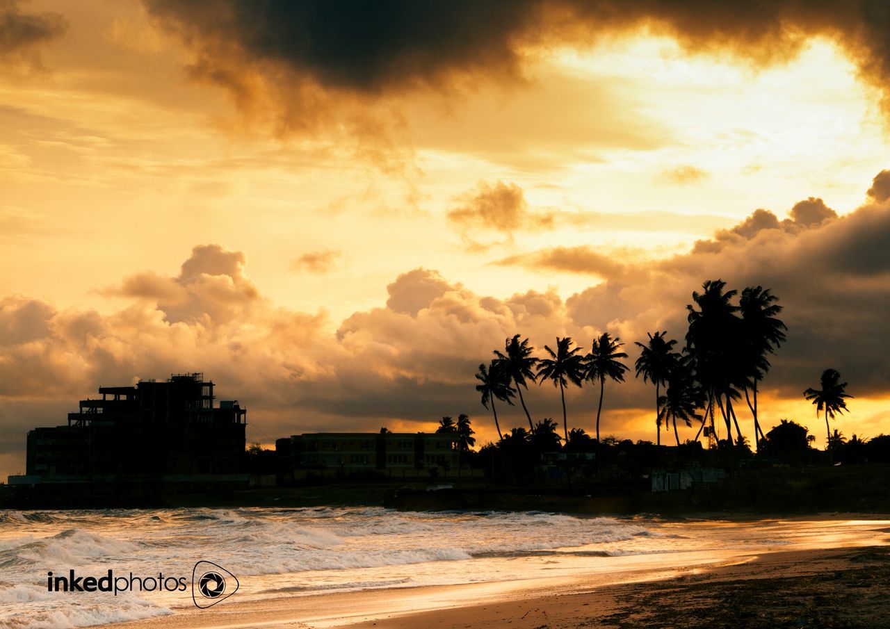 sunset, sky, built structure, architecture, building exterior, beach, sea, cloud - sky, tree, water, sand, palm tree, shore, orange color, silhouette, scenics, beauty in nature, nature, city, tranquility