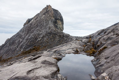 Rock formations on snow covered mountain against sky