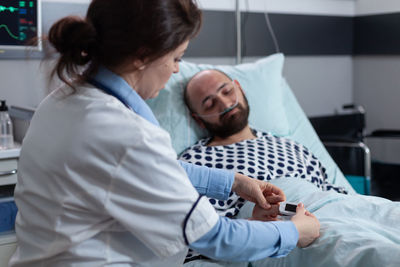 Doctor checking pulse rate of patient at clinic