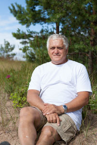 Portrait of mature man sitting on field