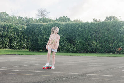 Young girl skateboarding alone at a basketball court