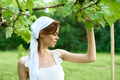 Side view of young woman standing on field