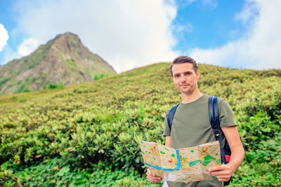 Portrait of young man standing against mountain