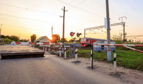 Railroad tracks by road against sky during sunset