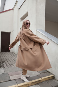 Female fashion model, posing for a full length photo, wearing total beige outfit, street fashion