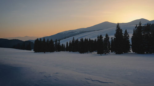 Scenic view of snow covered mountains against sky during sunset