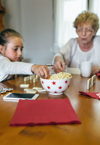 Mother and daughter while sitting on table at home