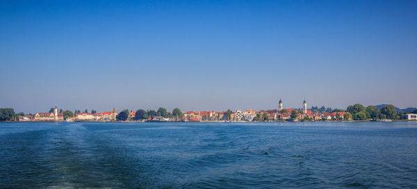 Sea by buildings against clear blue sky