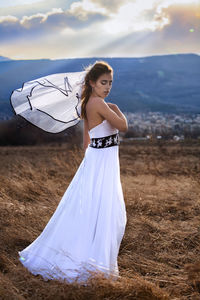 Beautiful woman standing on field against sky