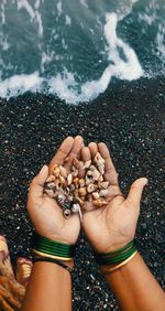High angle view of hand holding pebbles at beach