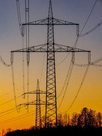 Low angle view of silhouette electricity pylon against sky during sunset