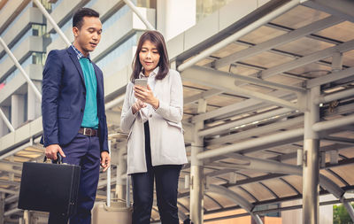 Low angle view of business people using phone in city