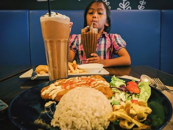 Cute girl enjoying food and drinks served on table in restaurant