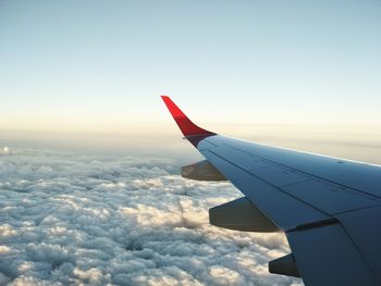 Close-up of airplane wing over cloudscape