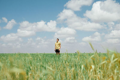 Man in open field with clouds. 