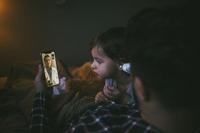 Rear view of children using mobile phone at home