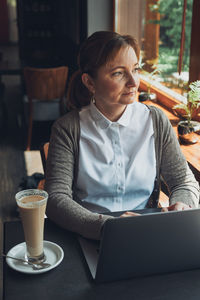 Relaxed businesswoman working remotely on her laptop computer contemplate managing her work