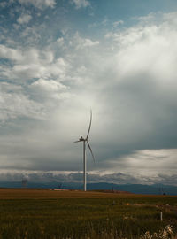 Wind turbines on field against sky