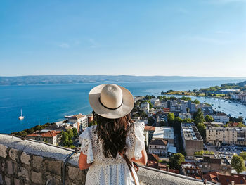 Rear view of woman standing on viewpoint above seaside town of omiš in croatia during summer holiday