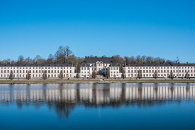 Reflection of building in river against clear blue sky