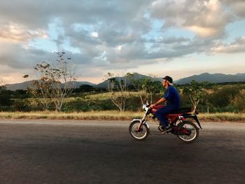 Man riding motorcycle on road against sky