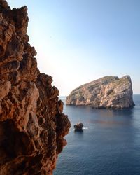 Rock formation on sea against clear sky