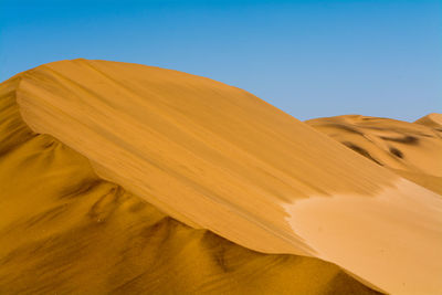 Scenic view of desert against clear blue sky