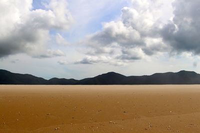 Scenic view of beach against cloudy sky