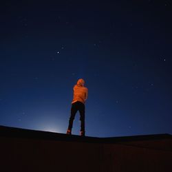 Low angle view of man standing against clear blue sky