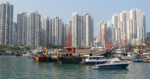 Sailboats moored in sea against buildings in city