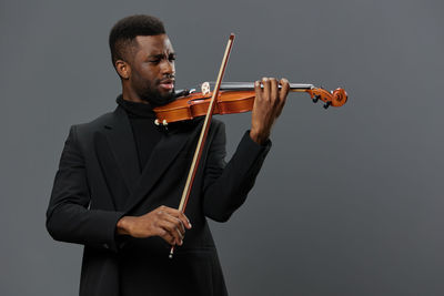 Midsection of woman holding violin against white background