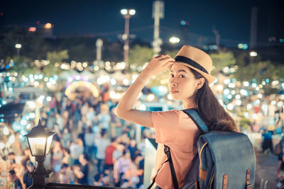 Portrait of young woman looking at illuminated city at night