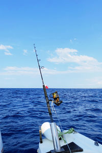 Fishing rod on sea against blue sky