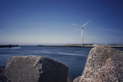 Wind turbine at beach against sky