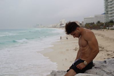 Young man on beach against sky