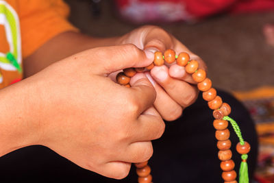 Midsection of child holding prayer beads