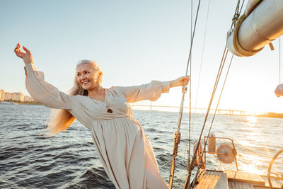 Senior woman standing at sailboat in sea