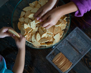 Hands making malaysian triple chocolate dessert.  crushing the cookies into tiny pieces.