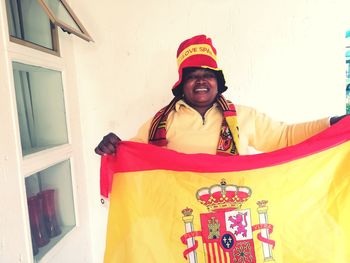 Portrait of smiling woman in hat with flag standing at home