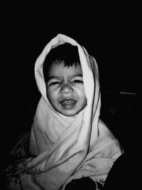 Portrait of cute baby boy wrapped in blanket at home