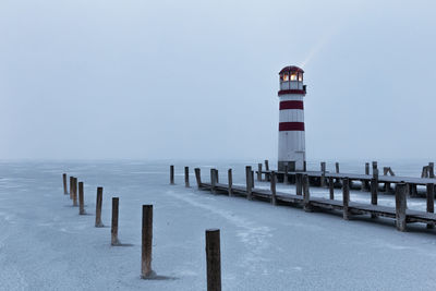 Lighthouse on sea against clear sky