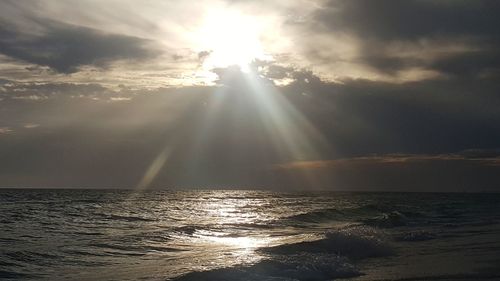 Sunlight streaming through clouds over sea