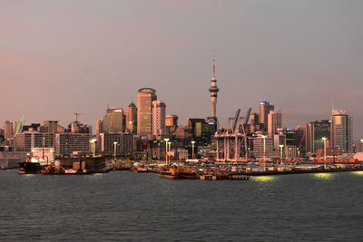 Sea and buildings in city against sky