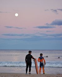 Rear view of men standing on beach