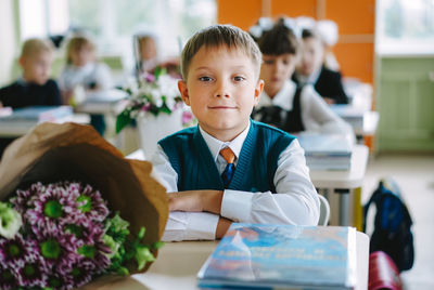 Cute russian boy sitting at the desk in a classroom of new modern scool on 1st september