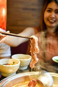 Smiling holding meat on chopsticks