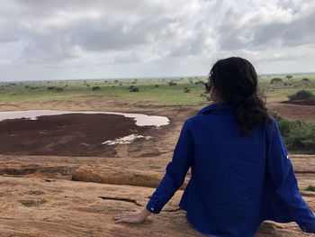 Rear view of woman standing on landscape against sky