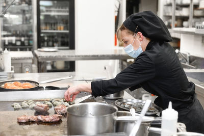 Side view of woman preparing food in commercial kitchen