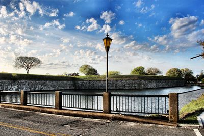 Built structure on retaining wall by river against sky