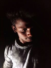 Portrait of young man standing against black background